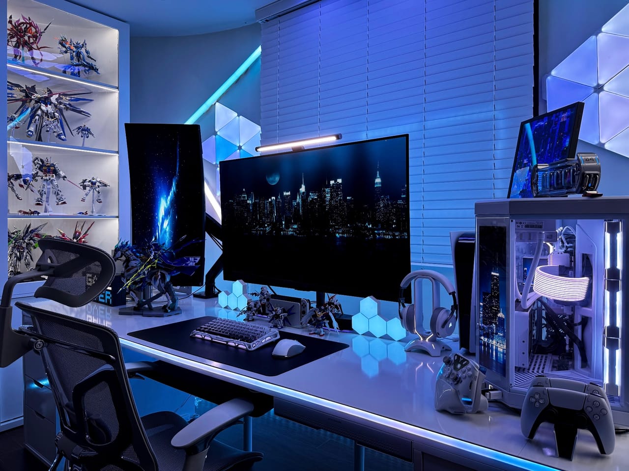 Góc máy của Dương Nghiệp Linh: Góc setup tông xanh dương và trắng với ba màn hình, case PC kính, đèn RGB và tủ trưng bày mô hình Gundam.