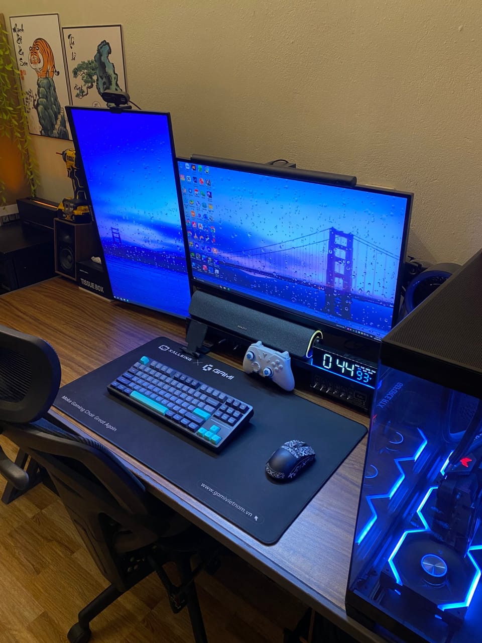 Góc máy của Ngô Đức Minh: Góc máy tông đen xanh dương với hai màn hình dọc và ngang, bàn phím cơ, case PC kính LED RGB trên bàn gỗ.