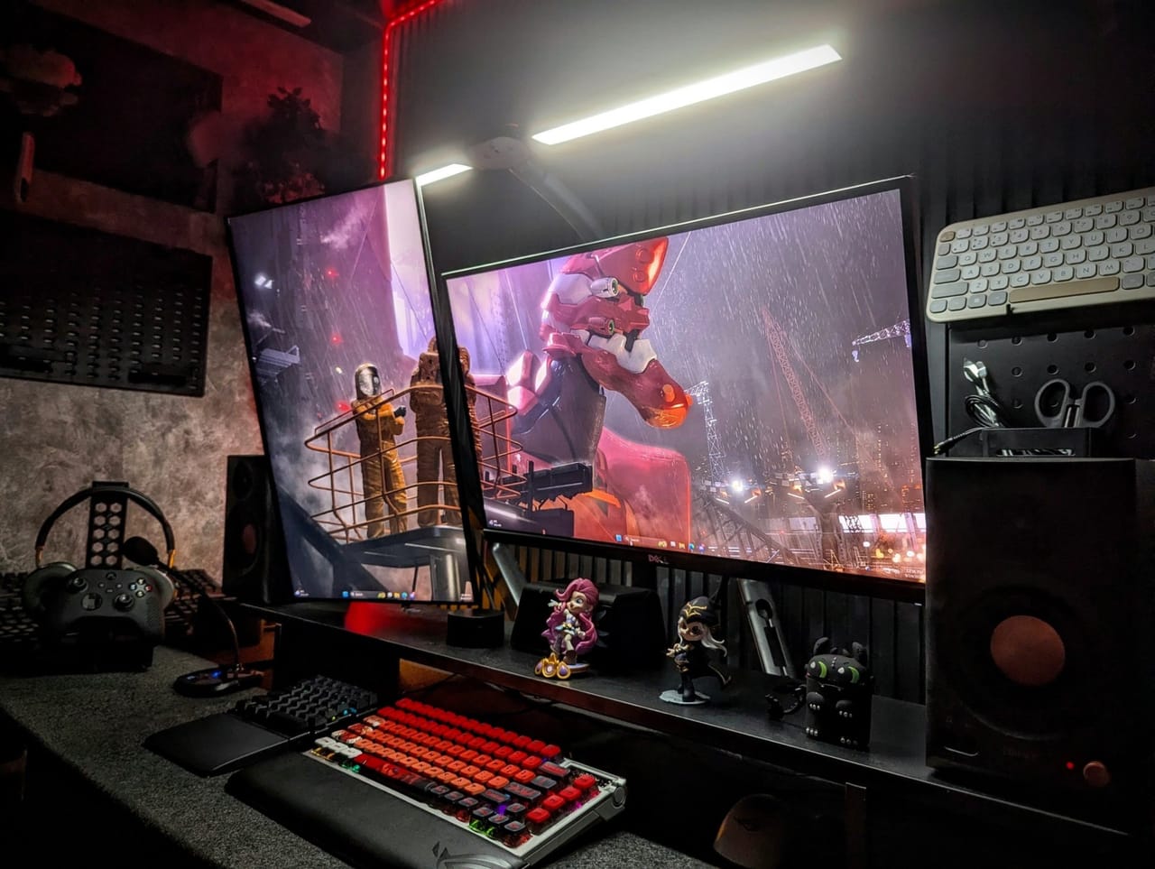 Góc máy của W1zardne: Góc setup tông đen đỏ với hai màn hình, bàn phím cơ RGB, loa, tay cầm, tai nghe và vài mô hình nhân vật trang trí.