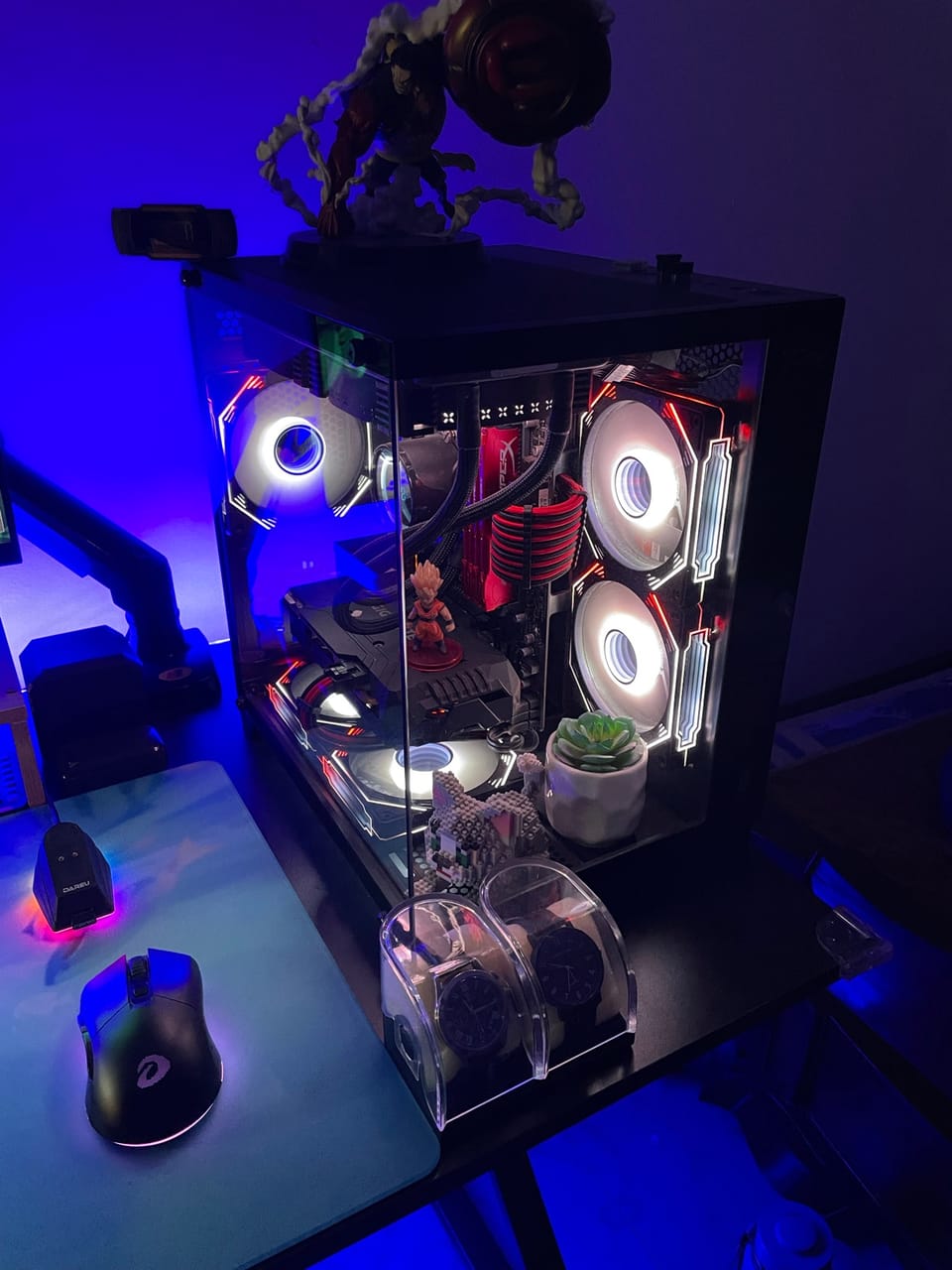 Góc máy của Rexx: Góc máy với case kính trong suốt, quạt LED trắng viền đỏ, ánh đèn xanh dương neon cùng mô hình anime và chuột Dareu.
