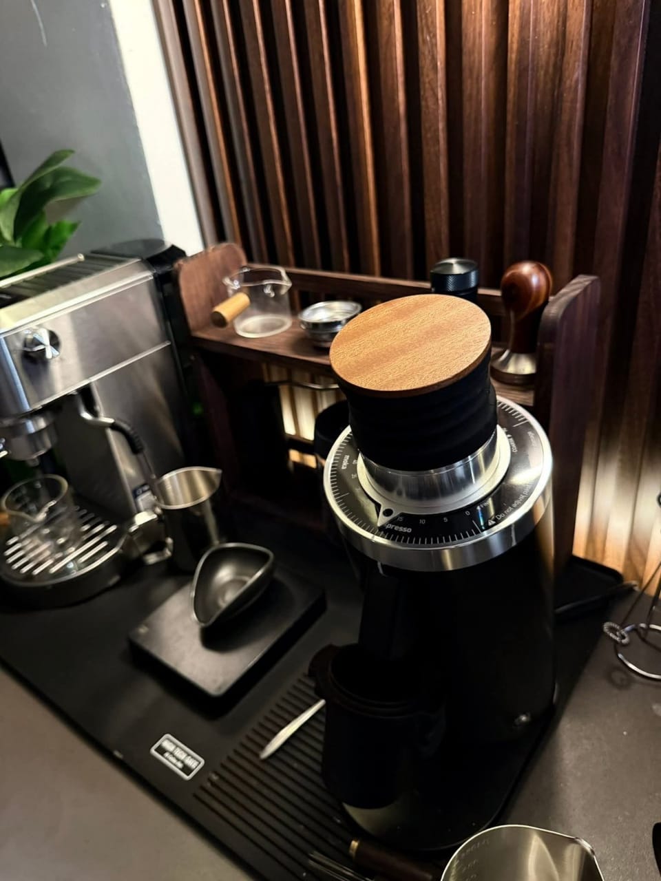 Góc máy của Nguyễn Bảo Anh: Góc pha cà phê tối giản với máy xay và máy pha espresso trên bàn gỗ.