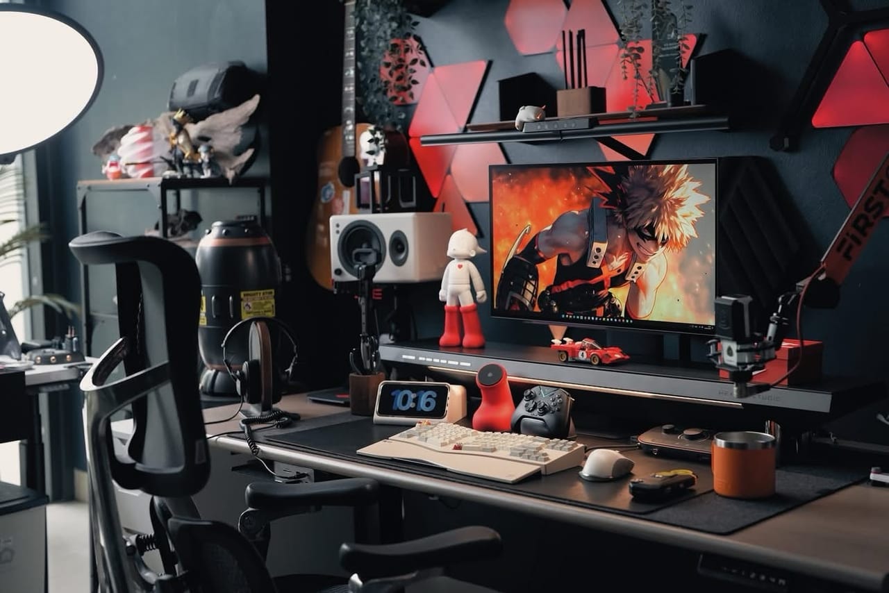 Setup góc máy của Xung Quanh Trung: Góc máy tông đen đỏ với đèn LED tam giác, figure anime, bàn phím trắng và micro streaming.