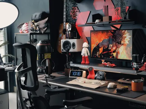 Góc máy của Xung Quanh Trung: Góc máy tông đen đỏ với đèn LED tam giác, figure anime, bàn phím trắng và micro streaming.
