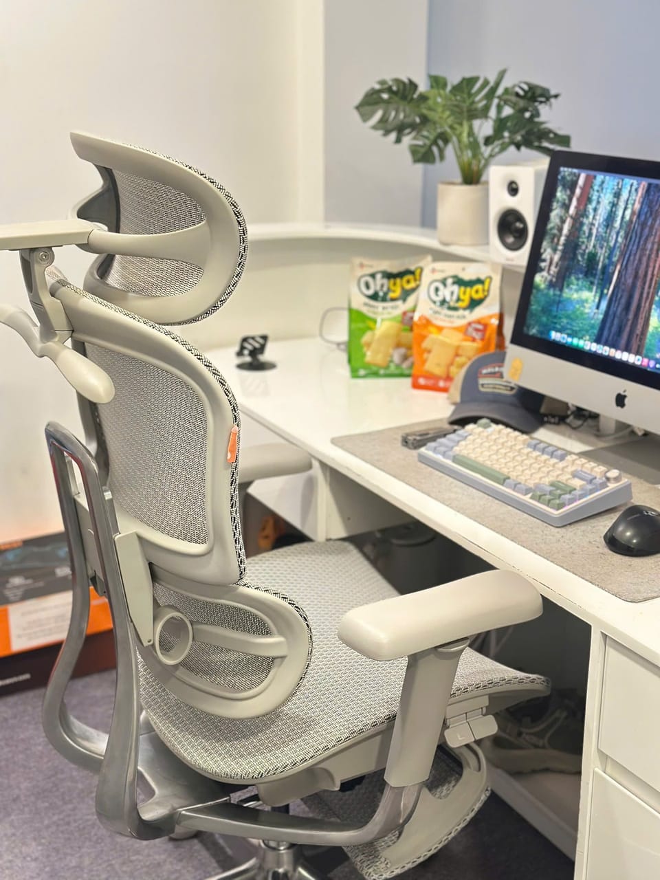 Setup góc máy của TheManson: Góc làm việc tông trắng sáng với ghế công thái học lưới, iMac, bàn phím cơ phối màu pastel, loa trắng và chậu cây xanh.