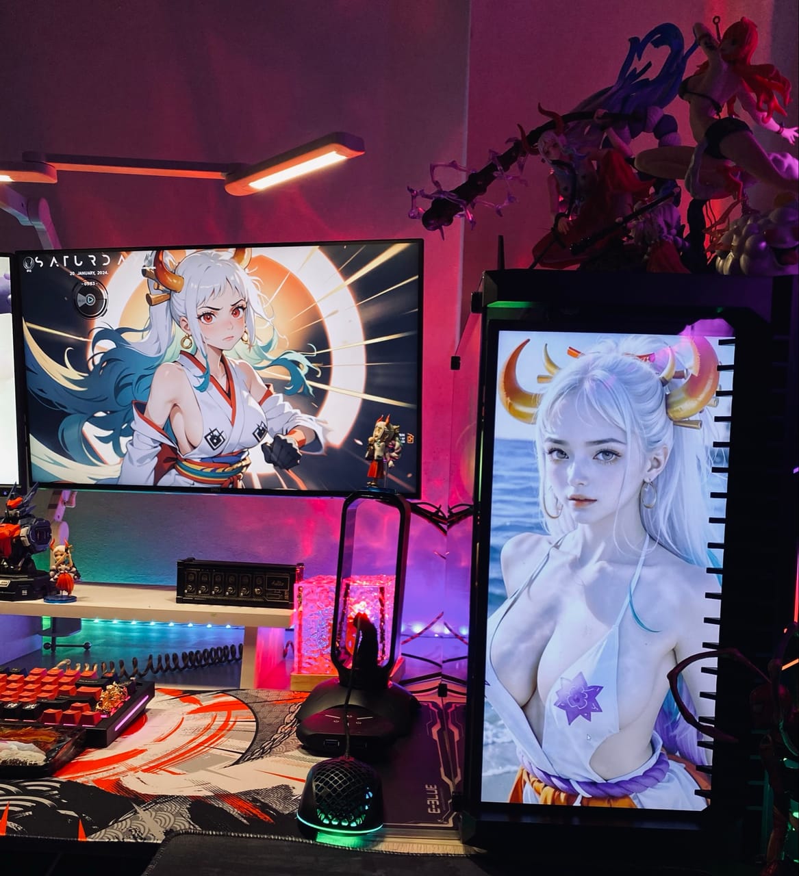 Góc máy của HieuPham Fingers: Góc máy phong cách anime với đèn RGB hồng tím, màn hình ngang, màn hình dọc gắn case, bàn phím cam đỏ và nhiều mô hình nhân vật.
