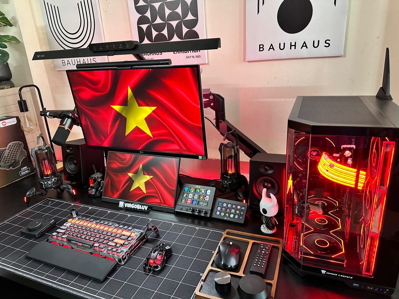 Góc máy của Đỗ Bảo: Góc máy tông đen đỏ với hai màn hình hiện cờ Việt Nam, case PC đèn RGB đỏ vàng, bàn phím cơ, micro và loa.
