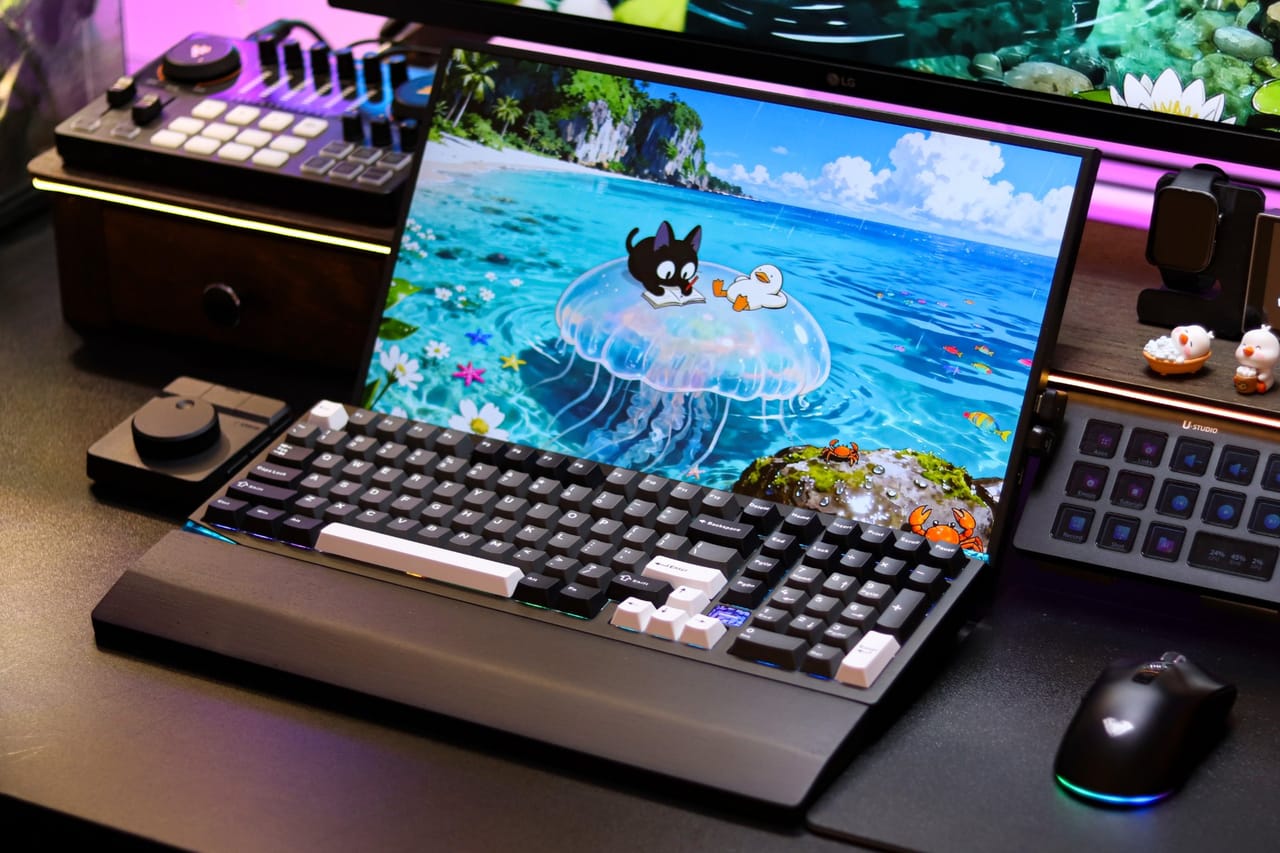 Góc máy của ĐÀO TIẾN HUY: Góc setup tối màu với bàn phím cơ đen trắng đặt trước màn hình hình biển, cùng mixer, bàn điều khiển phím LCD và đèn RGB hồng tím.