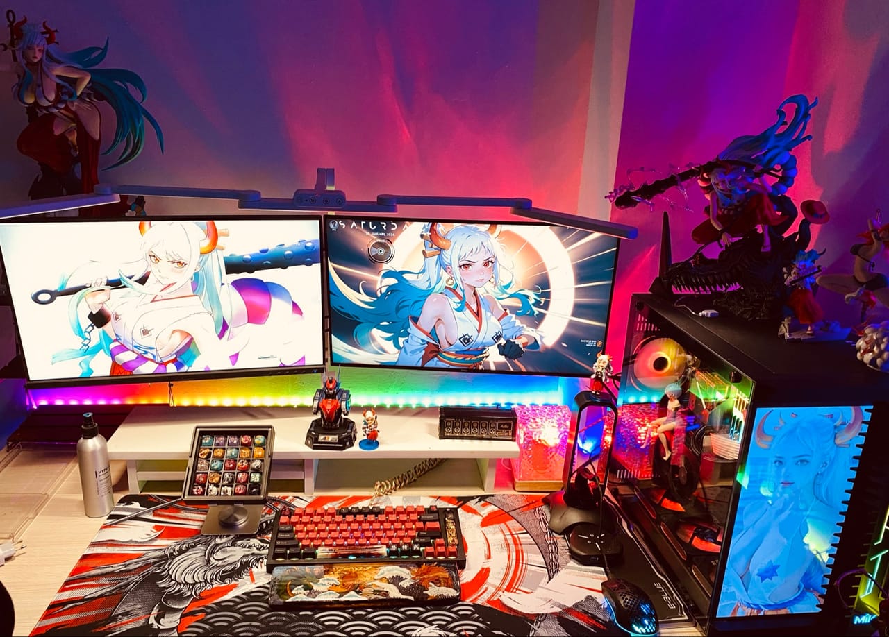 Góc máy của HieuPham Fingers: Góc máy hai màn hình ánh sáng RGB tím hồng rực rỡ, trang trí nhiều mô hình anime, bàn phím cơ đỏ đen và case kính.
