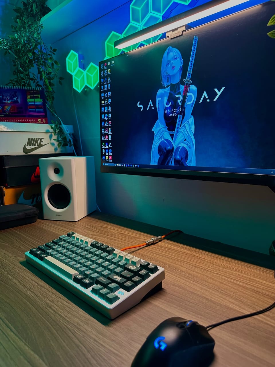 Góc máy của FuFu15: Góc setup ánh neon xanh dương và xanh lá với bàn phím cơ phối màu trắng xanh, dây cáp cam, loa trắng, chuột Logitech và cây xanh.