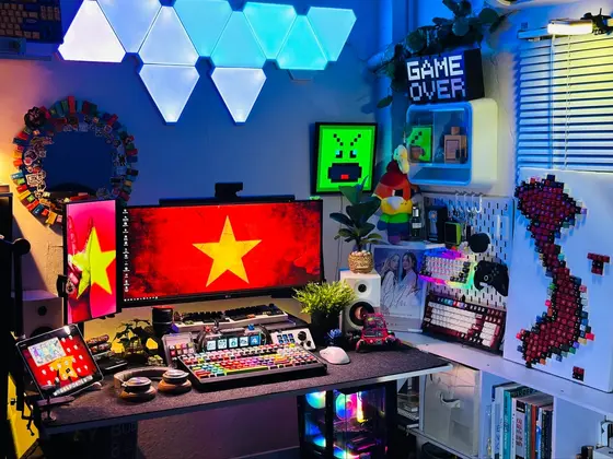 Góc máy của Thư Đoàn: Góc setup đậm chất Việt Nam với màn hình hình cờ đỏ sao vàng, đèn neon xanh, bàn phím nhiều màu và tranh bản đồ ghép từ keycap.