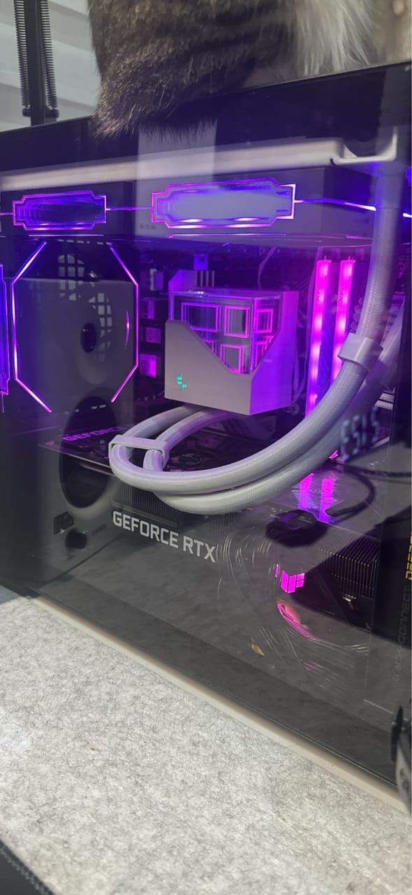 Góc máy của byEdward: Bên trong case PC kính cường lực với card GeForce RTX, tản nhiệt nước AIO trắng và đèn RGB tím hồng rực rỡ.