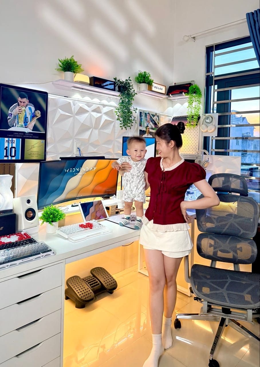 Góc máy của Tuấn Tiền Tỏi 🧄: Góc máy trắng sáng với màn cong Samsung, bàn phím cơ, cây xanh, tường 3D, đèn LED ấm và ghế công thái học.