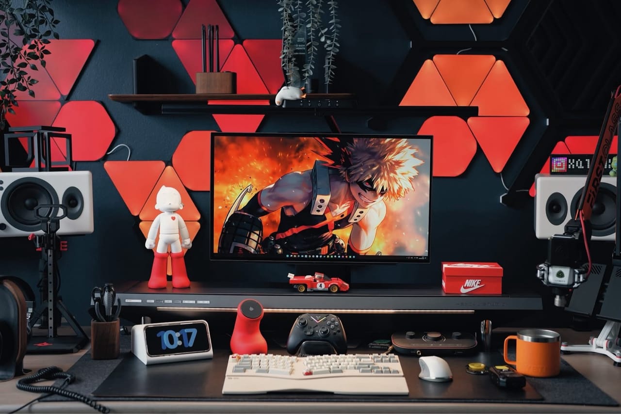 Góc máy của Xung Quanh Trung: Góc máy tông đen đỏ với đèn tam giác RGB, màn hình hình nền Bakugo, loa trắng, micro arm và nhiều figure trang trí.