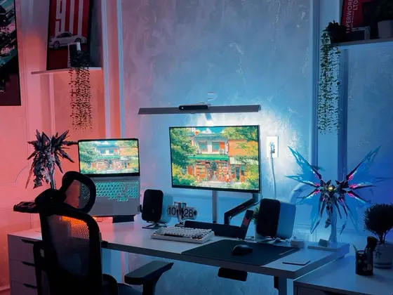 Góc máy của Wy: Góc máy tông trắng với đèn hắt hồng xanh, màn hình gắn arm, laptop, loa đôi và mô hình Gundam phát sáng.