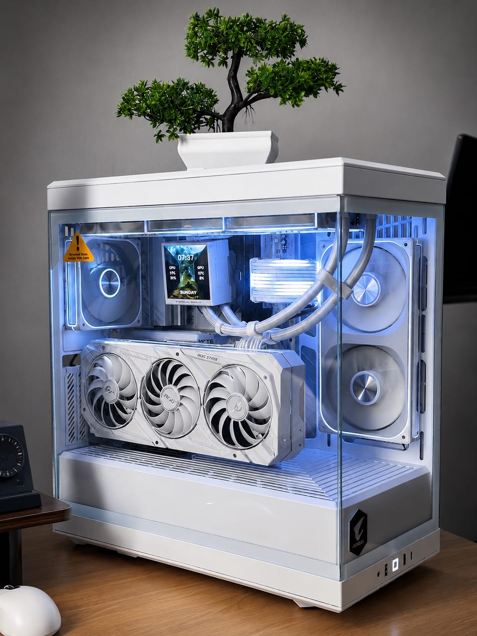 Góc máy của Bảo Lâm: Dàn PC toàn trắng trong case kính panorama, đèn LED xanh dương, card ROG Strix, chậu bonsai xanh đặt trên nóc case.