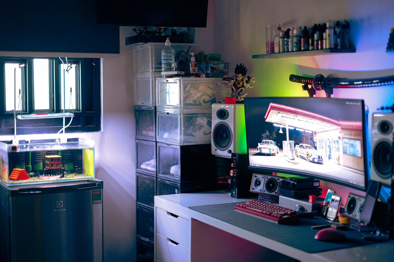 Góc máy của nhocdkj: Góc setup tối với đèn RGB nhiều màu, màn hình cong, bàn phím đỏ rượu, dàn loa, bể cá mini, tủ giày và mô hình anime.