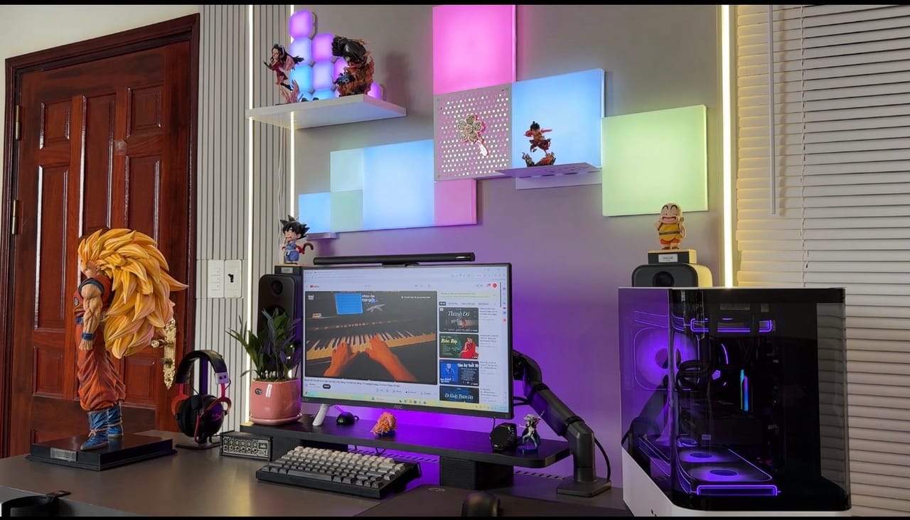 Setup góc máy của Thưởng: Góc máy RGB tím hồng với đèn panel gắn tường, case kính trong suốt và bộ sưu tập figure Dragon Ball, One Piece.