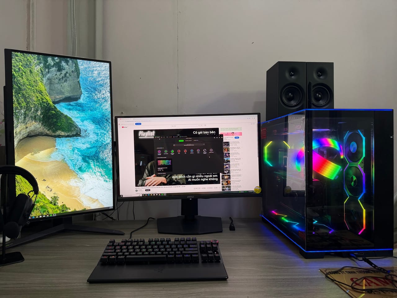 Góc máy của Thanh Tin: Góc máy tông đen với hai màn hình, một màn dựng dọc, case kính LED RGB rực rỡ và cặp loa bookshelf.