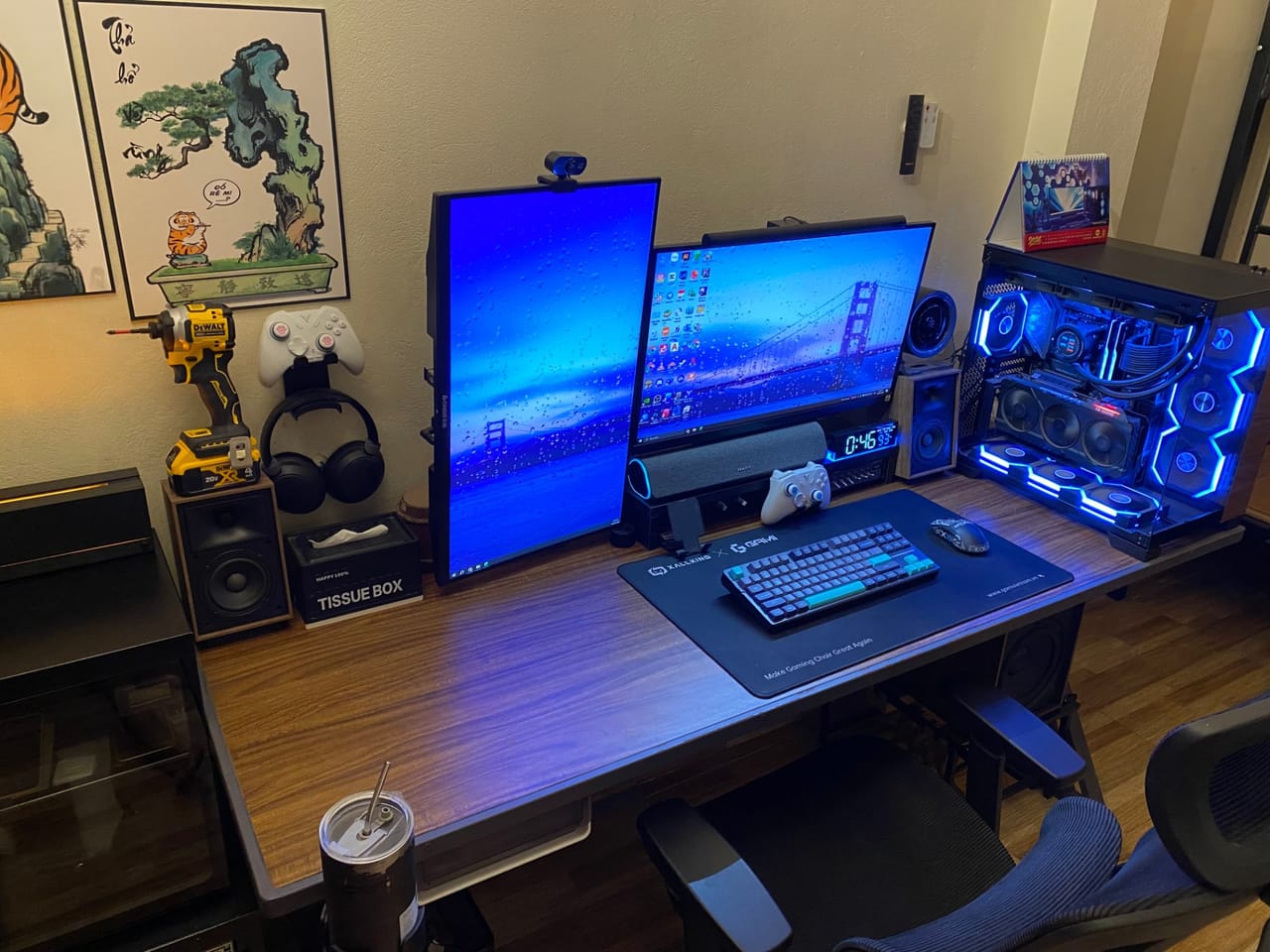 Góc máy của Ngô Đức Minh: Góc máy gaming bàn gỗ với hai màn hình dọc và ngang, PC case kính đèn RGB xanh dương, bàn phím cơ và dàn loa.