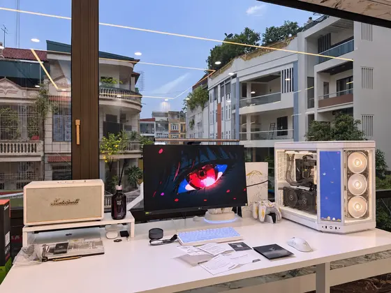 Góc máy của Thành viên VGS: Góc máy tông trắng tối giản bên cửa kính nhìn ra phố, case kính nhiều quạt, loa Marshall và màn hình LG.